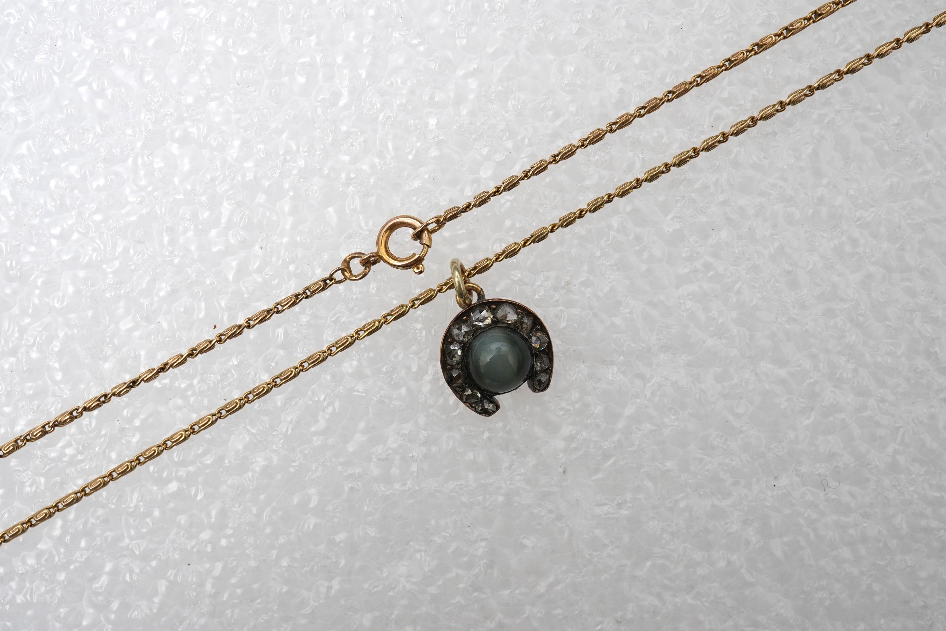 A yellow metal, cat's eye quartz and rose cut diamond cluster set horseshoe pendent, 11mm, together with a 9ct gold chain, 41cm, gross weight 5 grams.